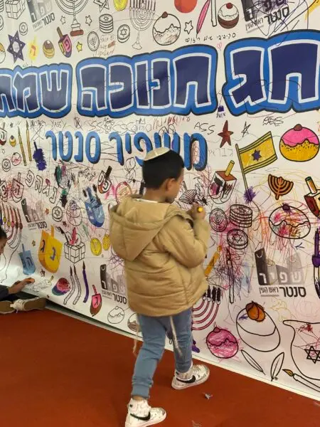 ילד מצייר על קיר גרפיטי באירוע קהילתי