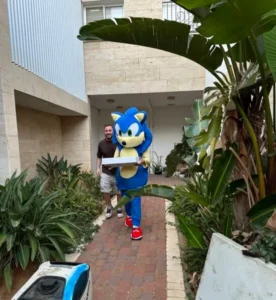 בובת תחפושת ענק של סוניק של ג’מבו הפקות מגישה עוגת יום הולדת